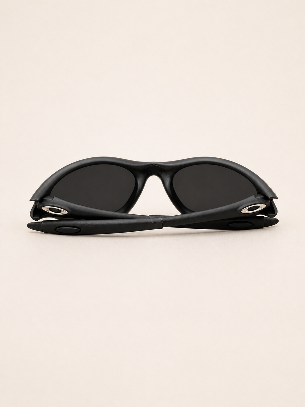 Rear view of black Oakley Minute sunglasses with the temple arms folded behind the dark lenses.