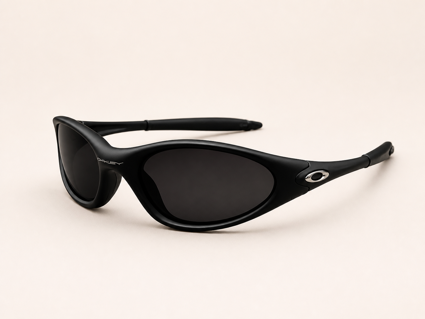 Three-quarter view of black Oakley Minute sunglasses with dark lenses, curved frame and silver oval temple accents.