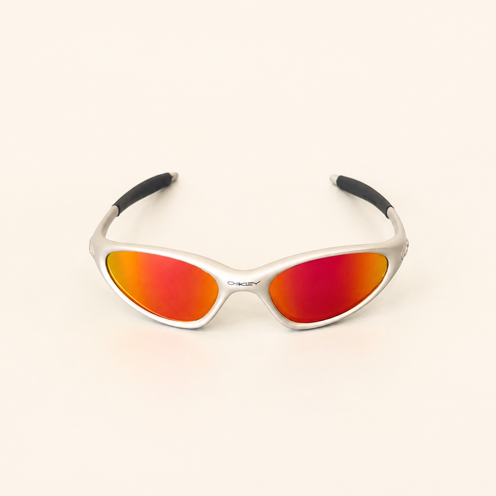 Angled view of Oakley Minute silver sunglasses with red-orange mirrored lenses and black temple sleeves.